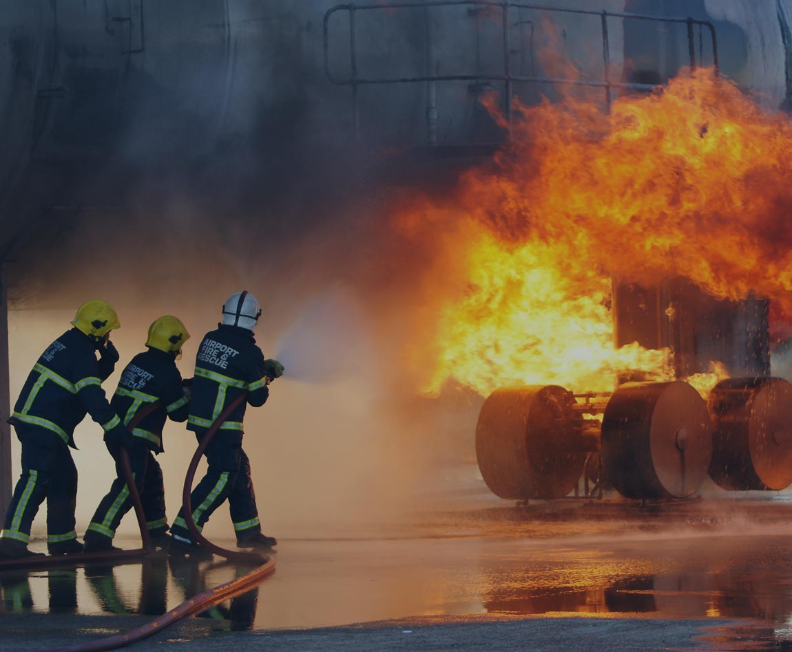 3 pompiers avec une lance à eau éteignant un feu sur le train d'atterrissage d'un avion