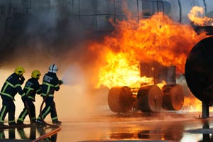 3 pompiers avec une lance à eau éteignant un feu sur le train d'atterrissage d'un avion