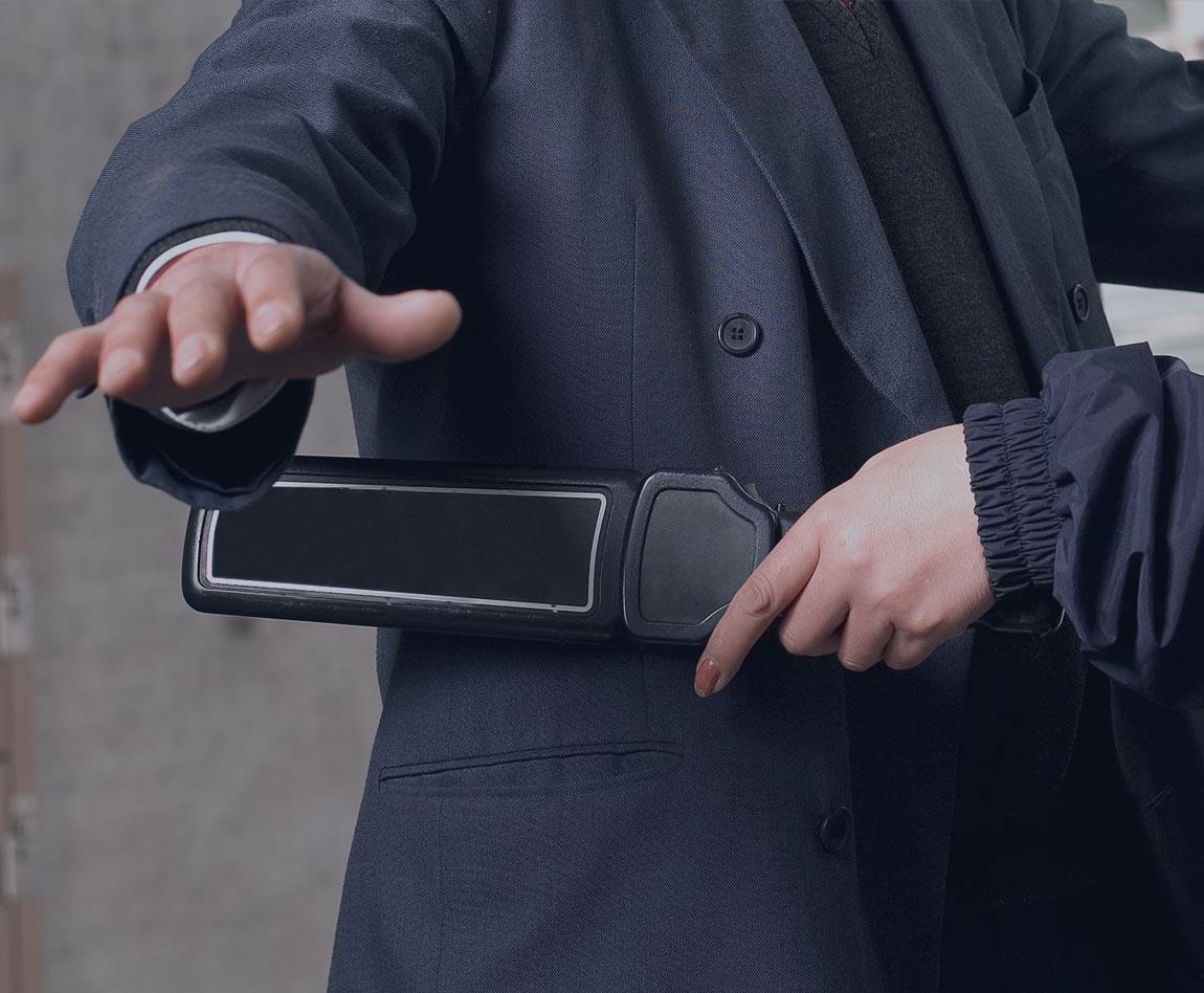 homme en train de passer un détecteur à métaux sur un passager