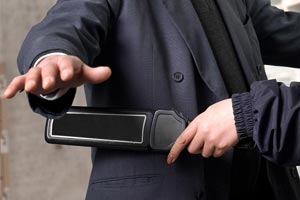 homme en train de passer un détecteur à métaux sur un passager