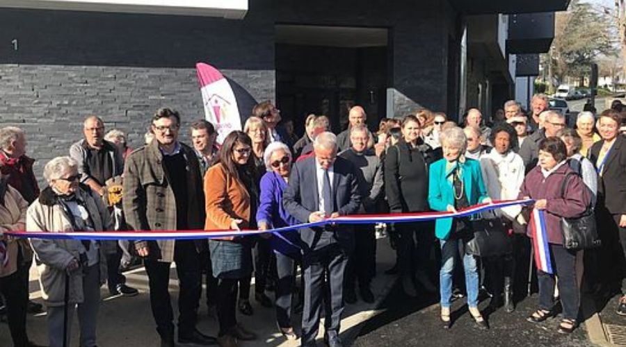 A group of people meeting for an inauguration, one person cuts a ribbon