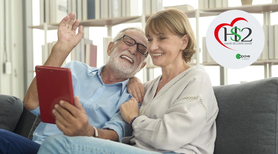 Seniors holding a touchscreen tablet on a sofa