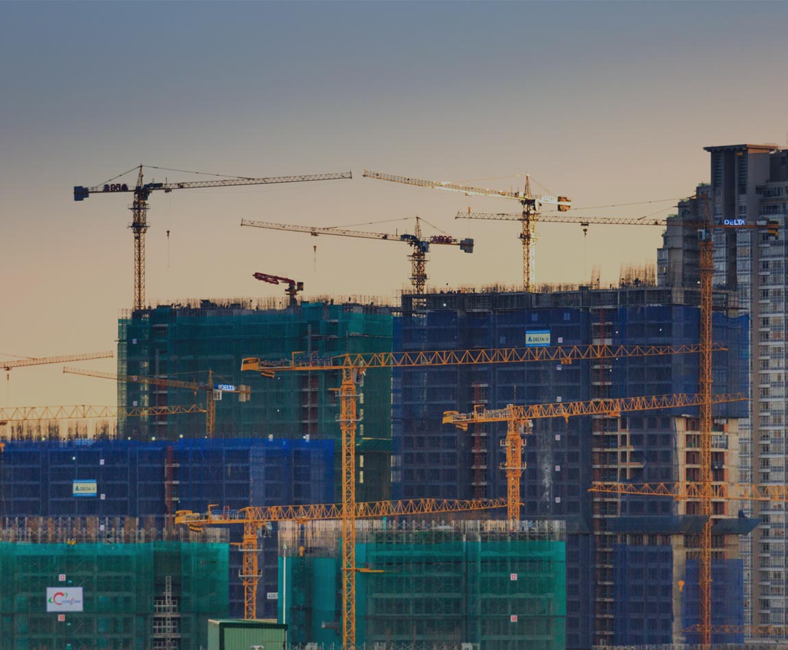several cranes in front of a large building complex