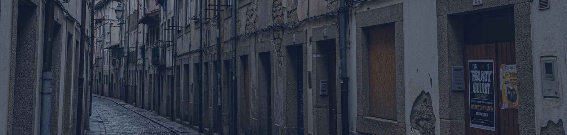 Une ruelle pavée étroite, bordée de vieux bâtiments en pierre et en crépi, avec du linge séchant aux fenêtres.
