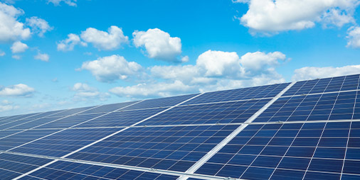 Des panneaux solaires en premier plan et le ciel bleu avec nuages en arrière plan