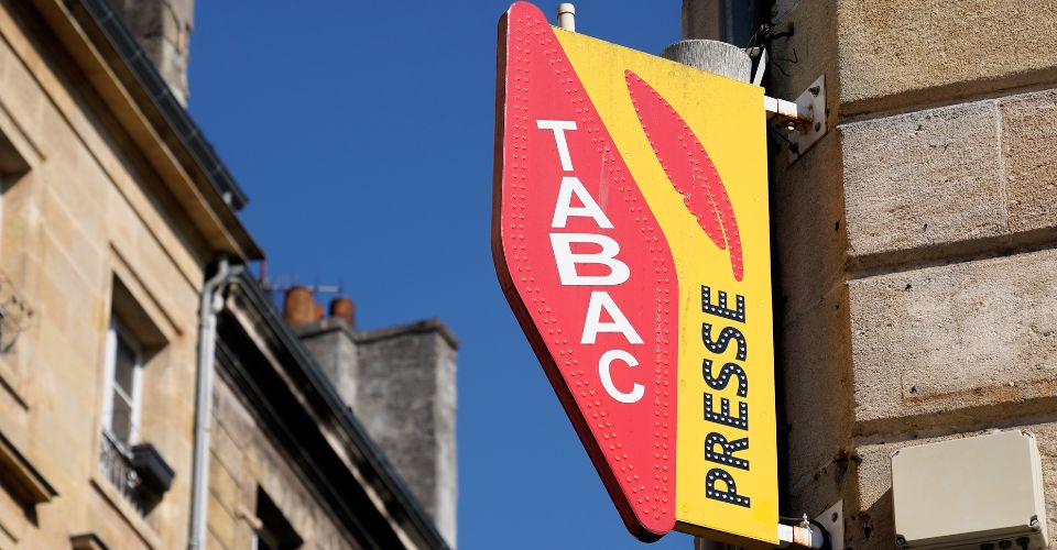 Enseigne rouge et jaune avec les mots "TABAC" et "PRESSE" sur la façade d'un bâtiment, représentant un commerce de proximité.