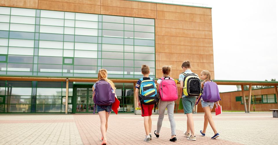 Élèves avec sacs à dos marchant vers l'école.