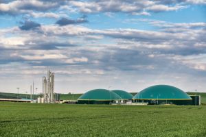 Usine de méthanisation ou de biométhane avec dômes verts et tours de distillation dans un champ.