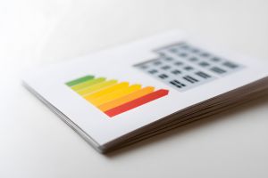 Une brochure est posée sur une table blanche, affichant un diagramme de performance énergétique avec des flèches allant du vert au rouge.