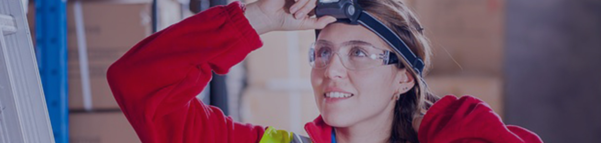 Une femme avec un gilet jaune, une lumière frontale et des lunettes de sécurité