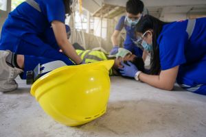 Secouristes en action autour d'un ouvrier blessé sur un chantier, casque de sécurité jaune au premier plan.
