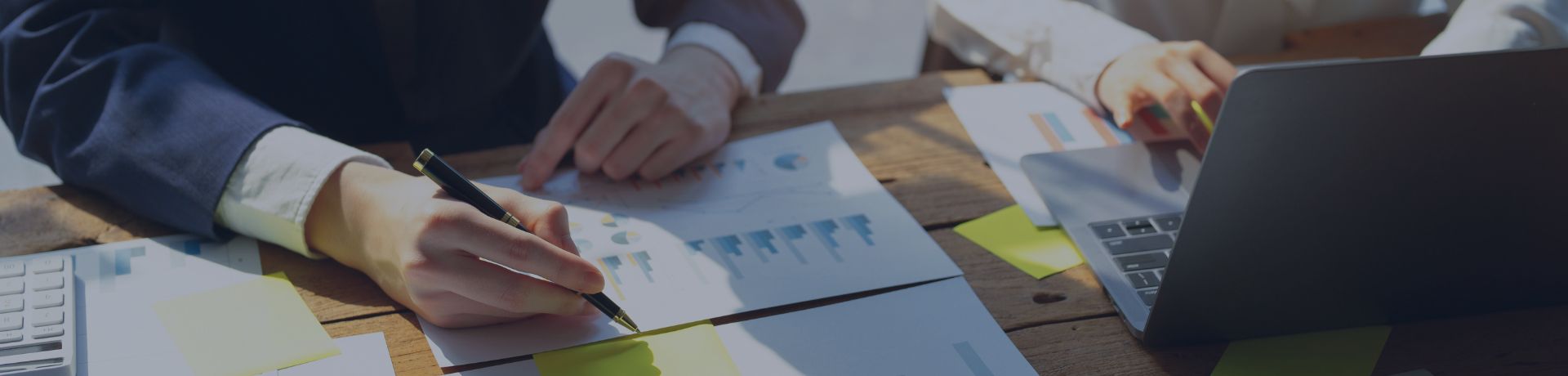 Deux personnes en réunion analysent des documents financiers et utilisent un ordinateur portable, illustrant la stratégie d'investissement et l'optimisation de la performance.