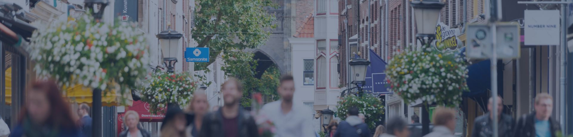 Une foule de gens déambule dans une rue pavée et animée, bordée de bâtiments historiques.