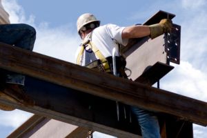 Ouvriers en hauteur installant une poutre métallique sur un chantier de construction.