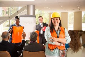 Femme en casque de chantier et gilet orange lors d'une formation sur la sécurité au travail (SST).