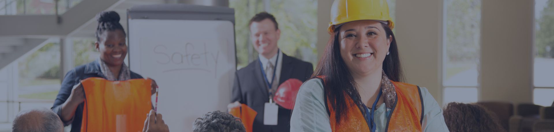 Femme en casque de chantier et gilet orange lors d'une formation sur la sécurité au travail (SST).