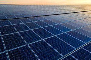 Panneaux solaires photovoltaïques bleus montés sur le toit d'un bâtiment pour produire de l'électricité propre et écologique au coucher du soleil.