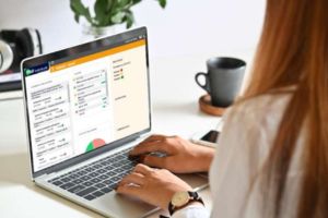 Une femme travaille sur un ordinateur portable affichant une interface utilisateur web.