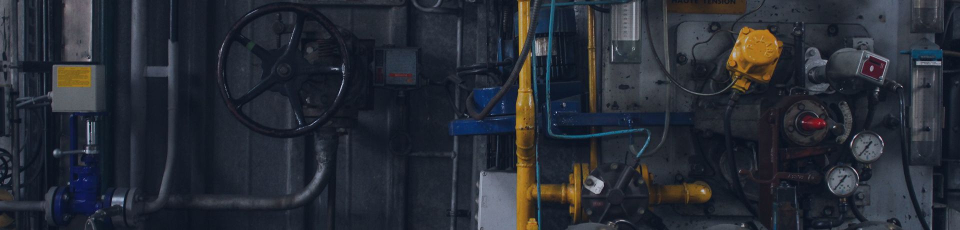 Gros plan d'une machinerie industrielle complexe avec des tuyaux, des vannes et des manomètres dans une usine à Courbevoie, en France.