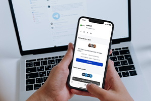 Une personne tient dans ses mains un smartphone qui montre une page recensant les webinaires d'Apave en France