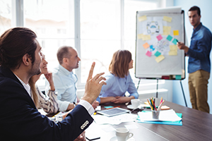 Un orateur appelle un collègue la main levée pendant une réunion.
