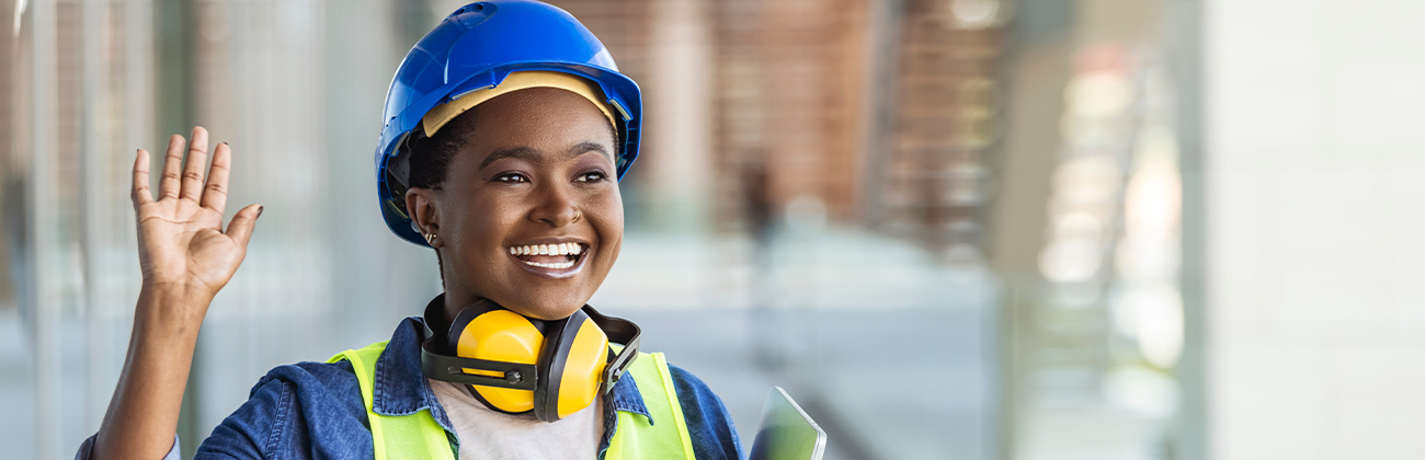 Portrait d'une jeune femme ingénieur avec un casque bleuet des plans dans les mains sur un chantier de construction.