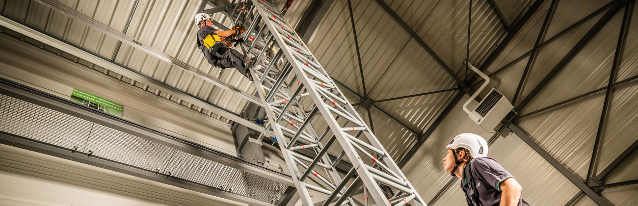 Deux stagiaires apave munis de harnais de sécurité montent une tour