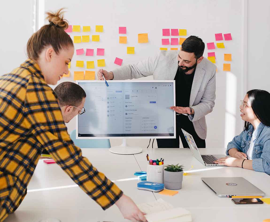 Un homme debout derrière un écran plat d'ordinateur entouré de son équipe