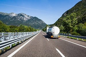 Un camion citerne roule sur l'autoroute avec une vue des Alpes en arrière plan.