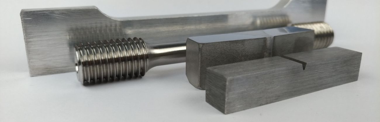 Diverses éprouvettes de laboratoire en métal, y compris une éprouvette de traction avec filetage et des éprouvettes pour essais de flexion.