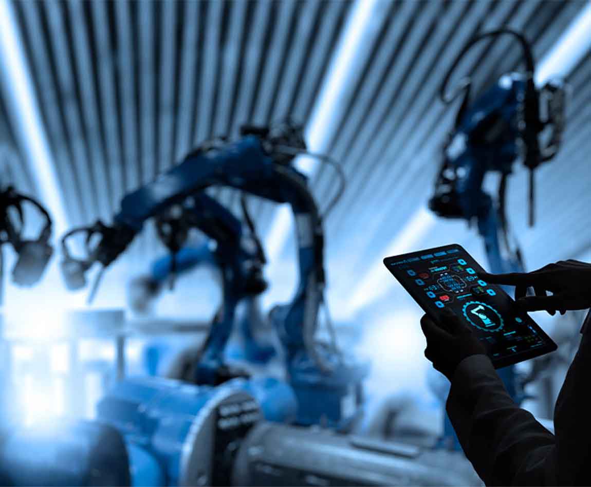 Une femme en train de vérifier sa tablette avec devant lui des bras articulés robotiques