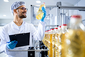 Un employé d'une usine contrôle une ligne de production de bouteilles d'huile