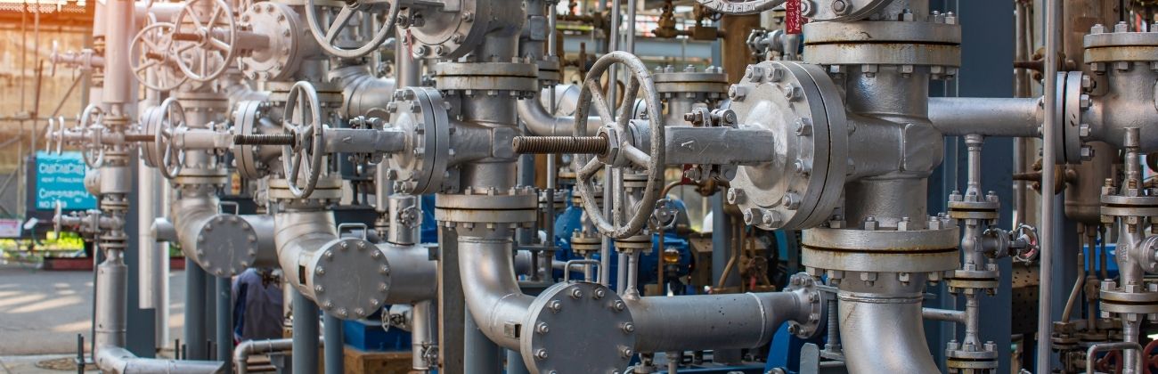Réseau complexe de tuyauteries industrielles métalliques avec vannes circulaires.