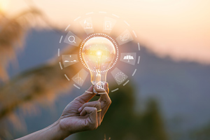 Main tenant une ampoule avec des pictogrammes représentant des sources d'énergie renouvelables