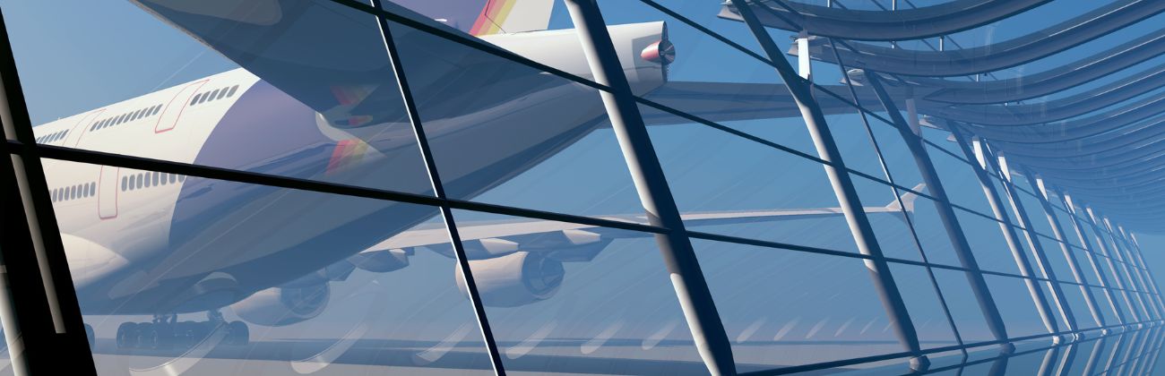 Vue à travers une façade vitrée moderne d'un aéroport, montrant l'arrière d'un avion de ligne blanc avec des couleurs vives sur sa queue.