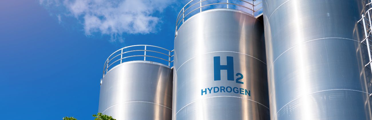 Cuves de stockage d'hydrogène (H2) en métal, sous un ciel bleu, représentant les infrastructures pour l'énergie hydrogène.