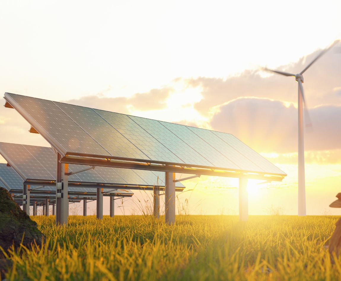 Solar panels and wind turbines in a rural landscape at sunset, symbolizing renewable energy and sustainability.
