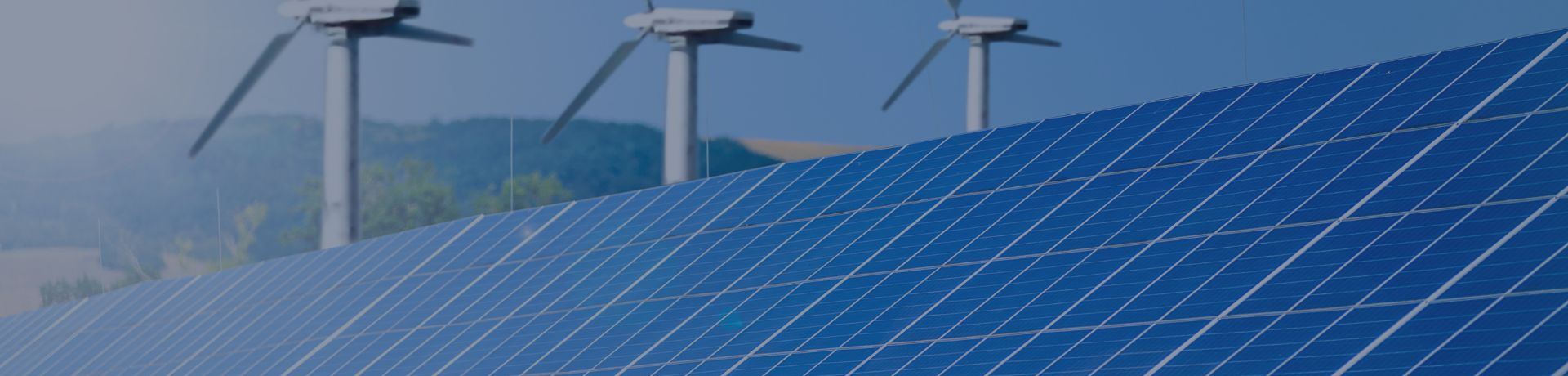 Des panneaux solaires bleus au premier plan, avec des éoliennes en arrière-plan, illustrant les énergies renouvelables.