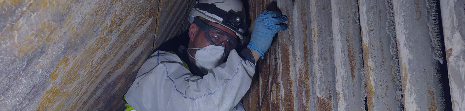 Collaborateur Apave en train de faire des prélèvements d'amiante sous une charpente