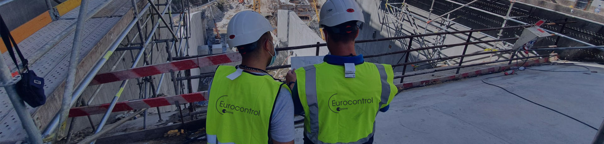 Deux hommes avec des casques et des gilets jaunes Eurocontrol Apave en train de réaliser un contrôle qualité pour des travaux de génie civil 