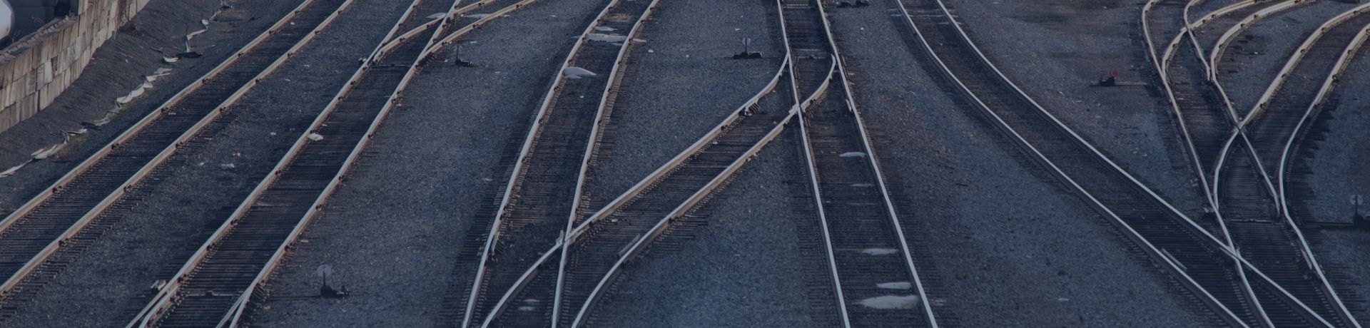 Vue aérienne de multiples rails de chemin de fer s'entrecroisant sur un lit de ballast gris.