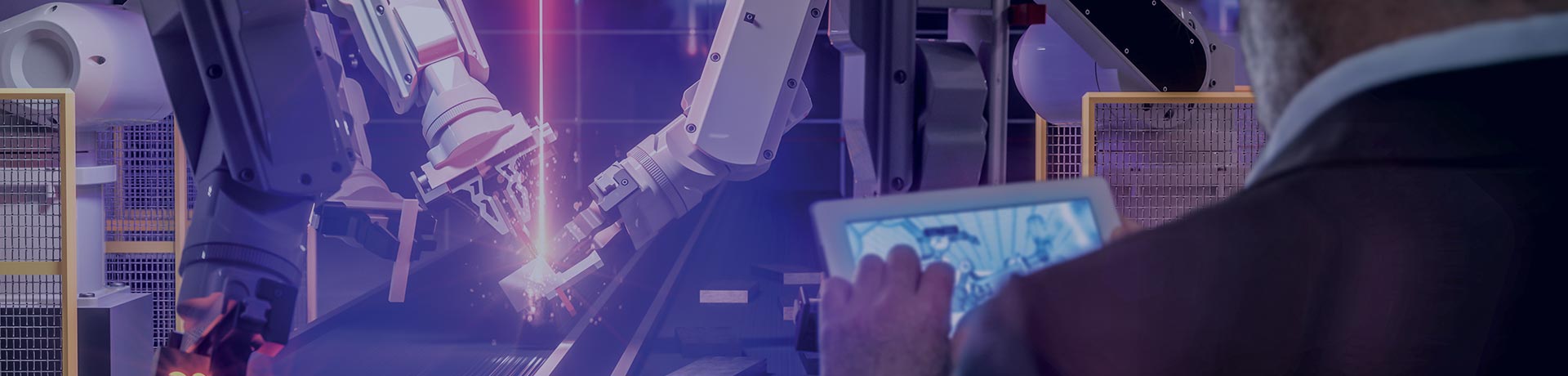 A man holds a tablet in his hands in front of robot arms