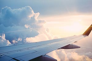 An aircraft wing in the sky with clouds in the background